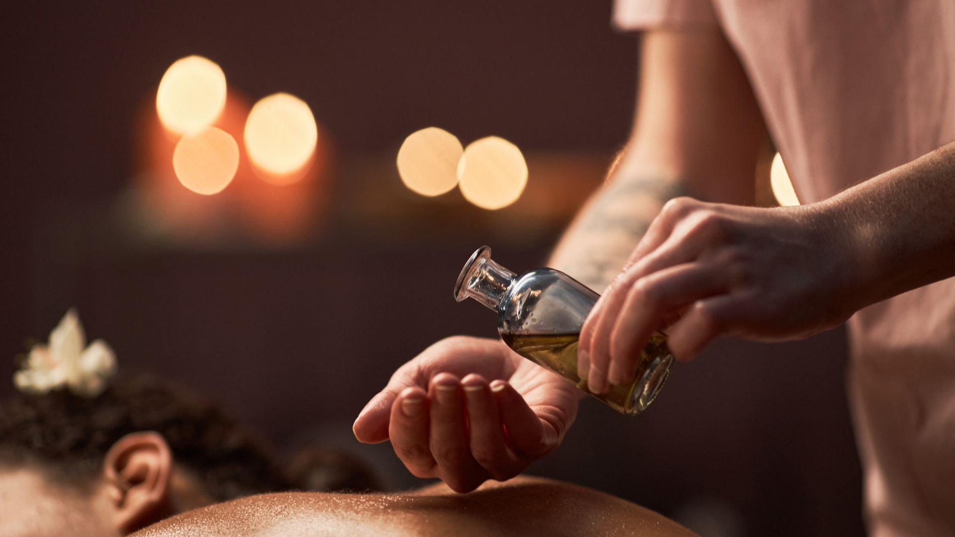 Massage therapist applying aromatherapy oil with candlelight in background