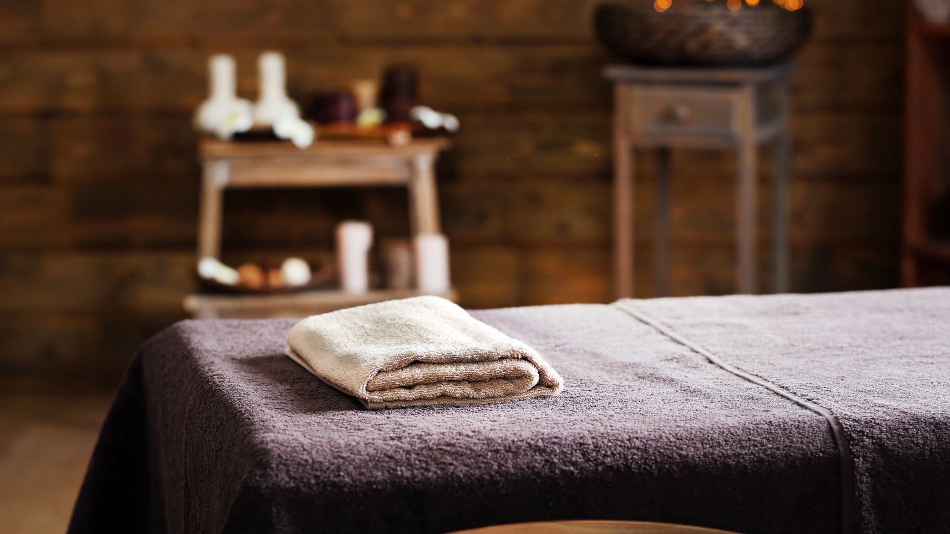 Massage table with towel in warm, cozy spa setting with blurred background