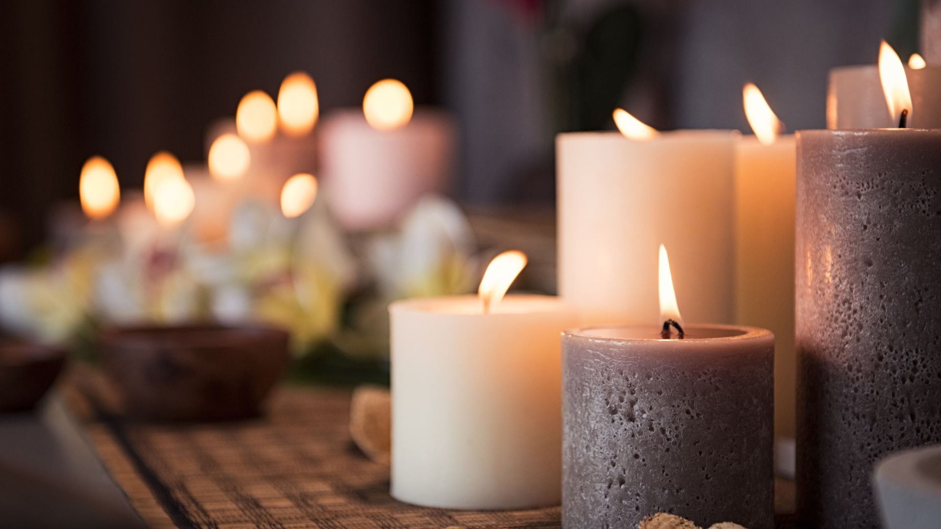 Lit candles of various sizes and colors creating a warm, peaceful atmosphere
