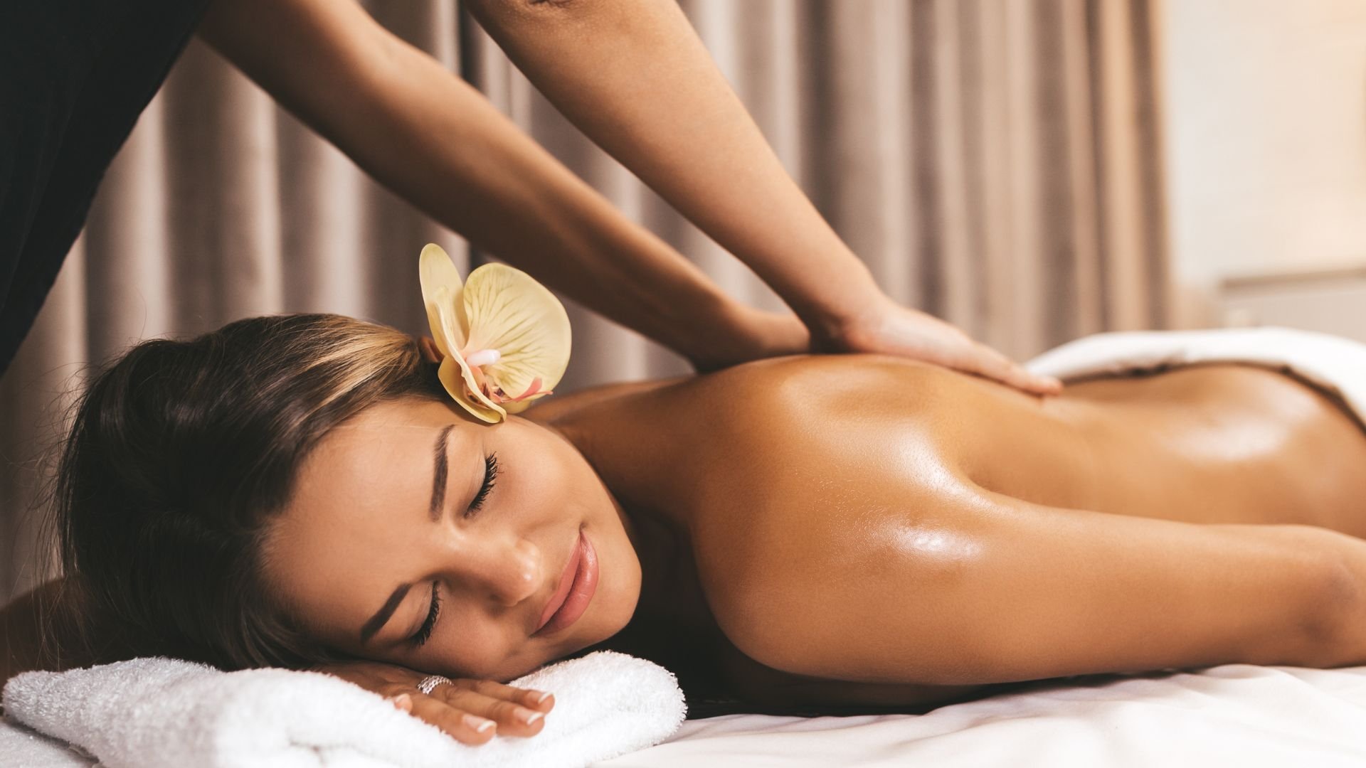 Woman receiving relaxing massage with orchid, peaceful spa treatment