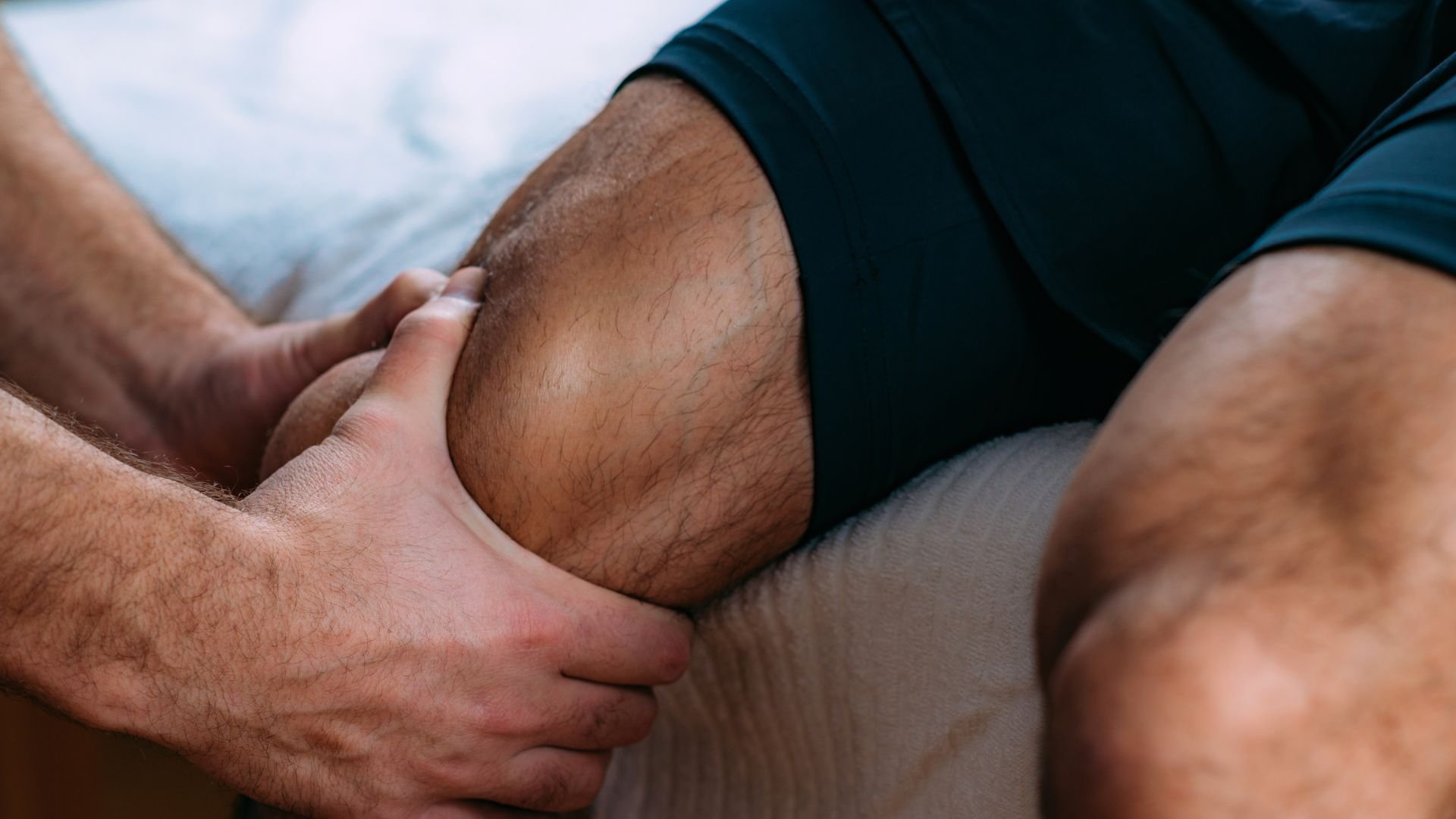 Hands examining knee during medical assessment or physical therapy