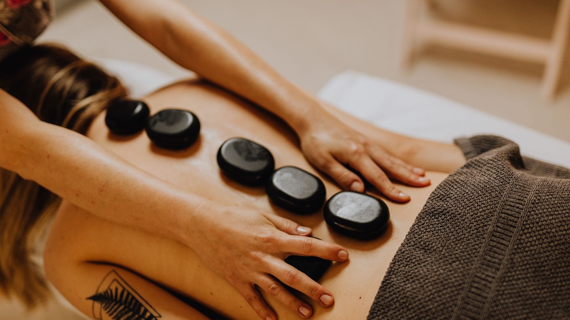 Hot stone massage therapy with smooth black stones on person's back