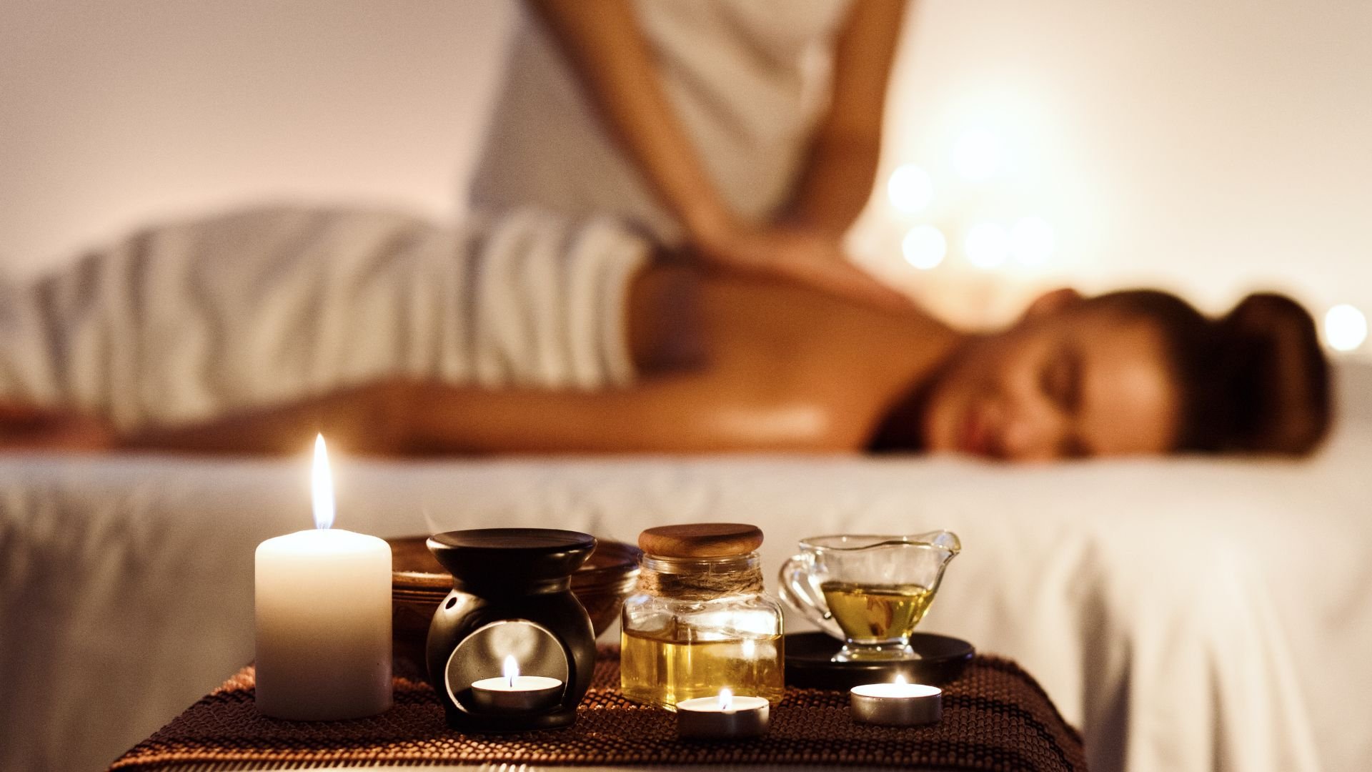 Relaxing spa setting with massage oils, candles, and blurred massage bed