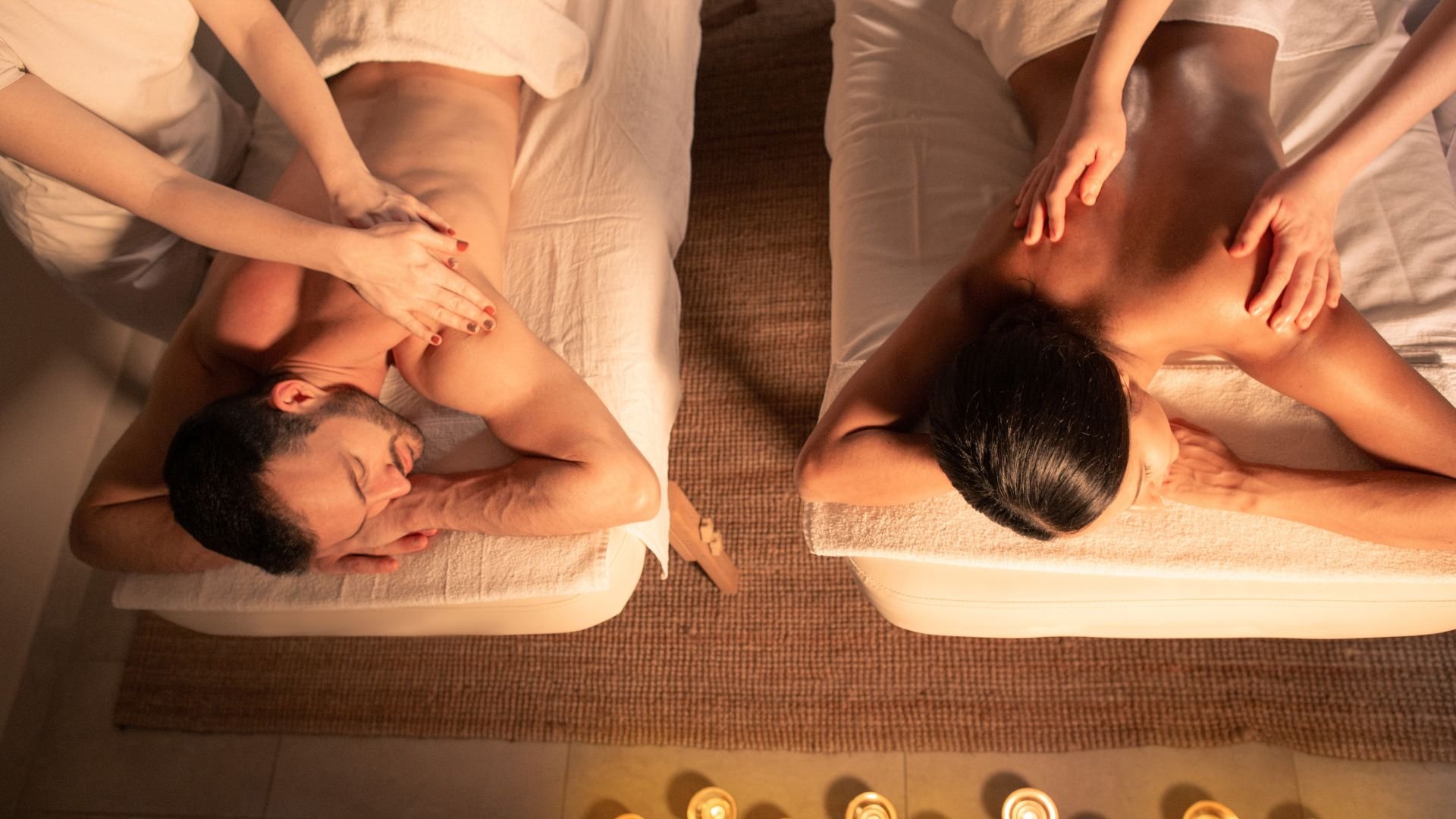 Two people receiving relaxing massage at spa with candles